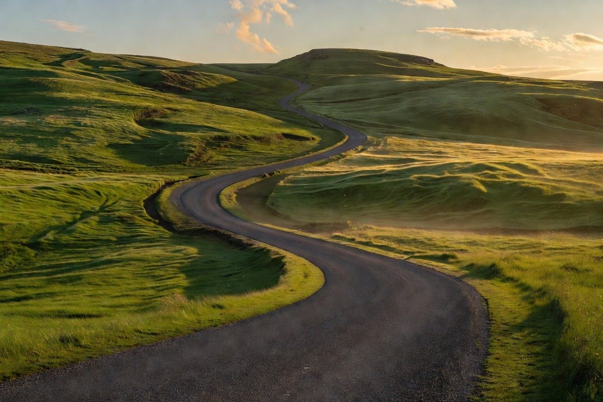 An empty road through green hills in late light